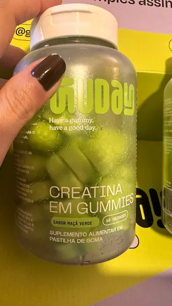 Cliente segurando o pote de Creatina em Gummies Guday